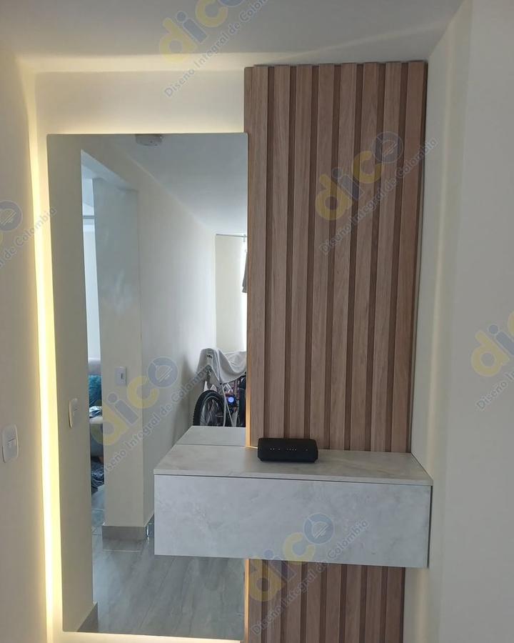 Recibidor con columna de listones de madera, repisa flotante y espejo con luz